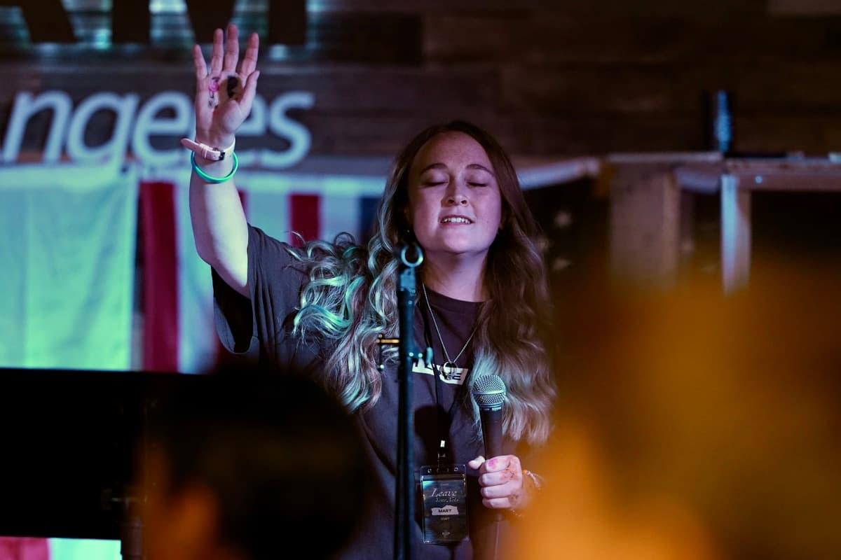 A YWAM Los Angeles staff member worshiping with her hand raised